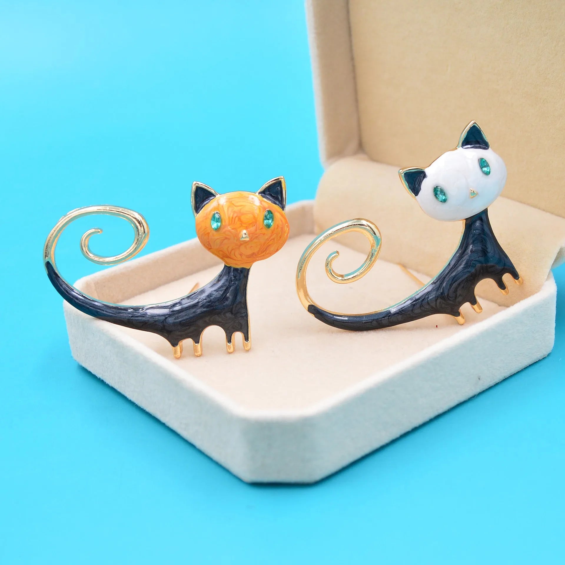 Close-up of a white alloy brooch with a painted tail-up kitten design.