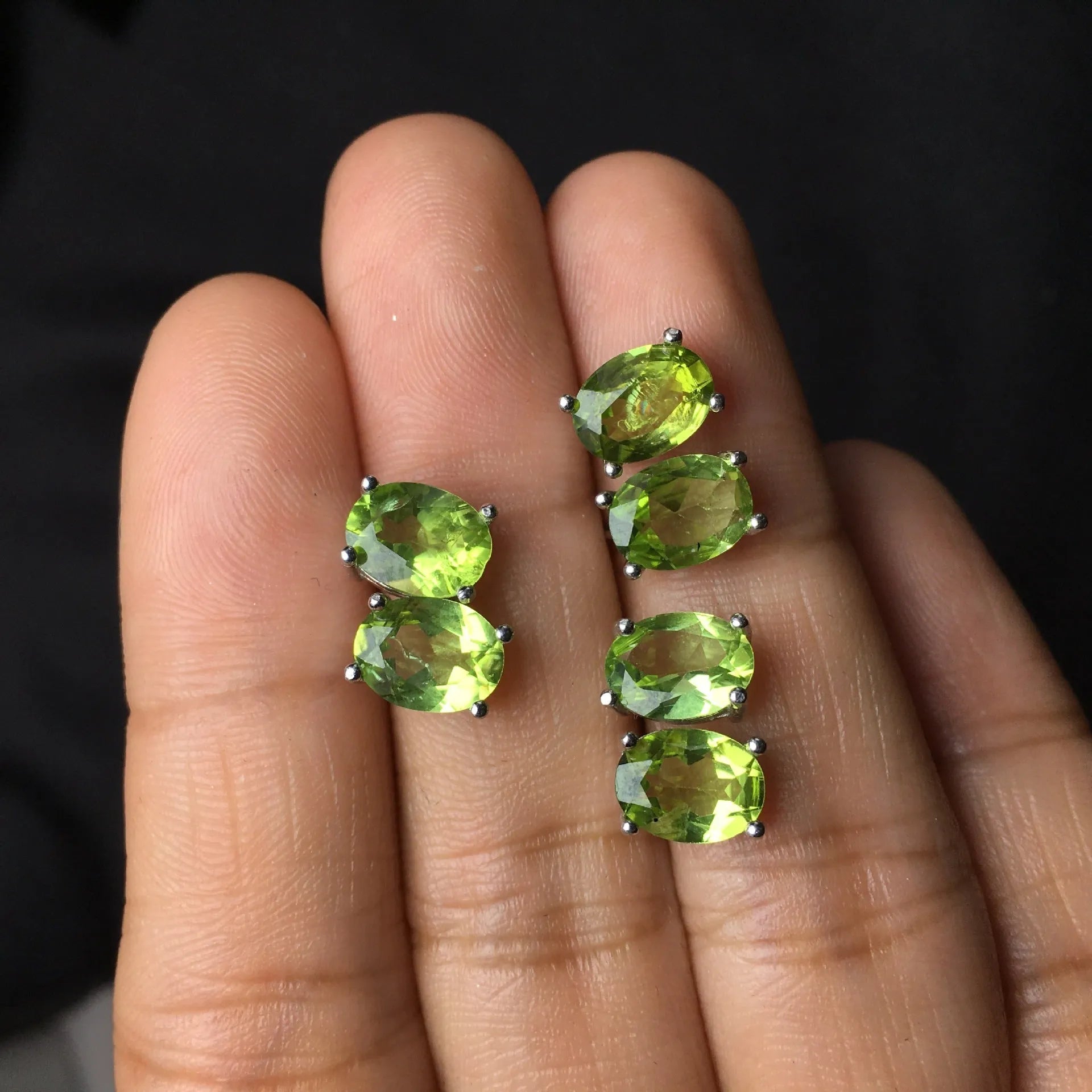 Close-up of grass green olivine stud earrings with elliptical 6x8mm stones in sterling silver setting.