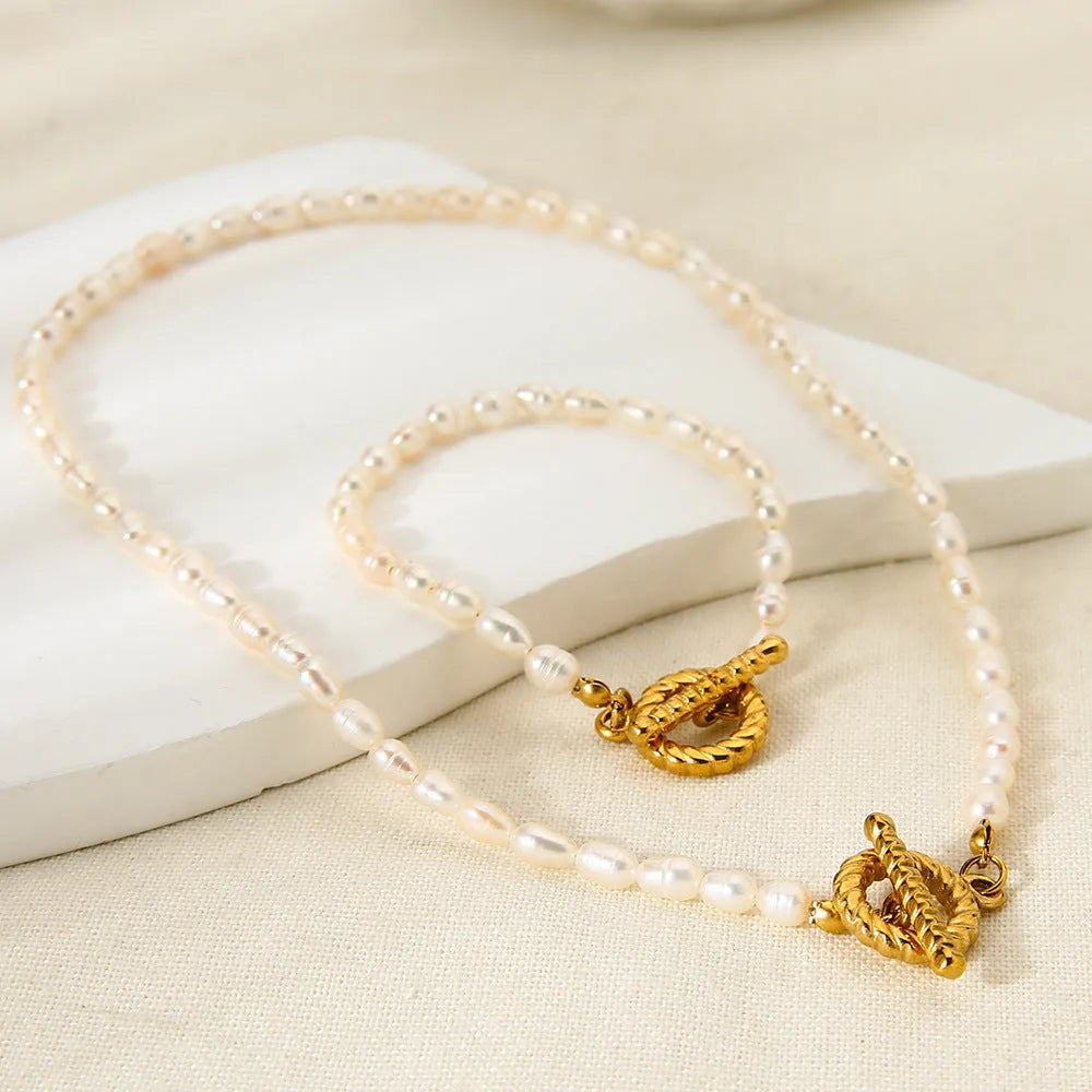 Freshwater pearl and stainless steel geometric pendant necklace and matching bracelet set for women.
