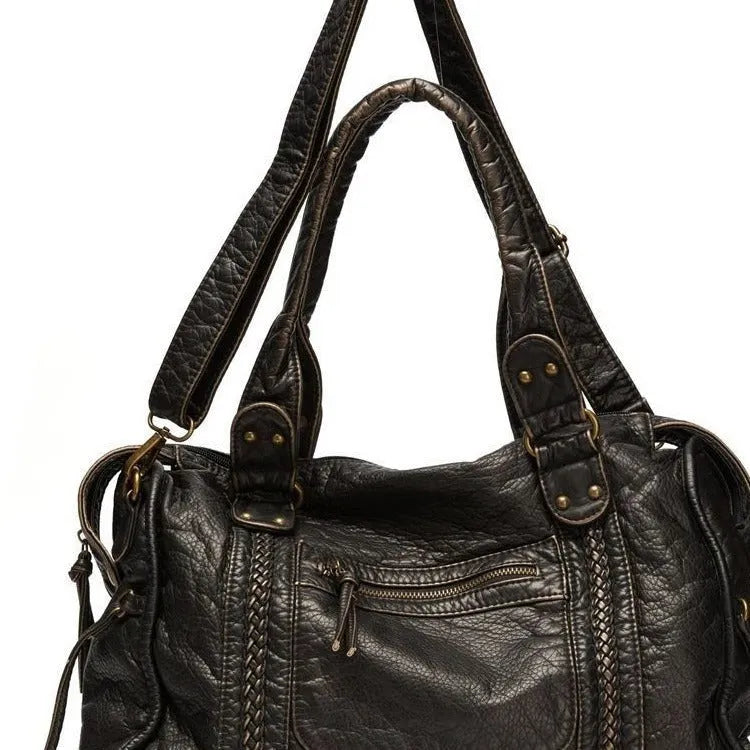 Women's retro messenger bag in bright black with golden edge, showing internal zipper compartments and weaving details
