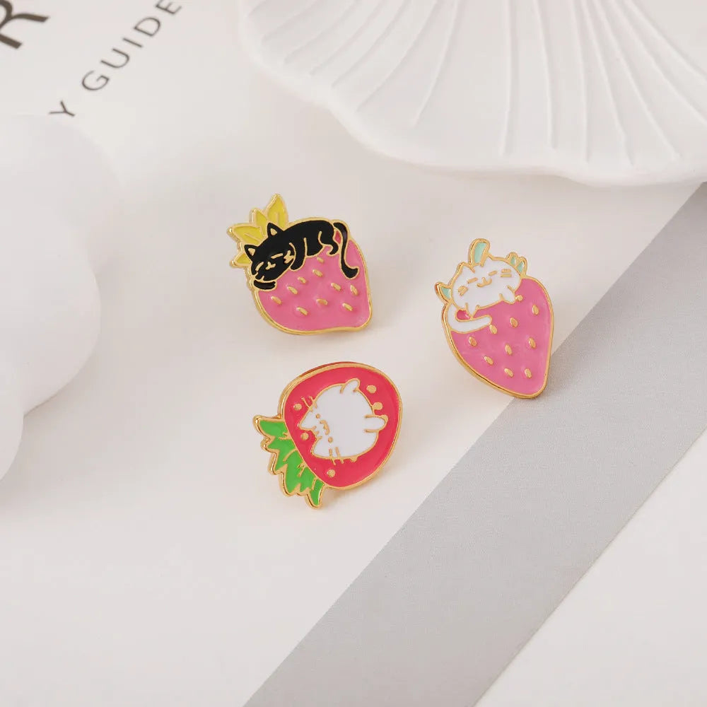 Alloy brooch with a cute cat, strawberry, and dripping oil design in metallic colours.