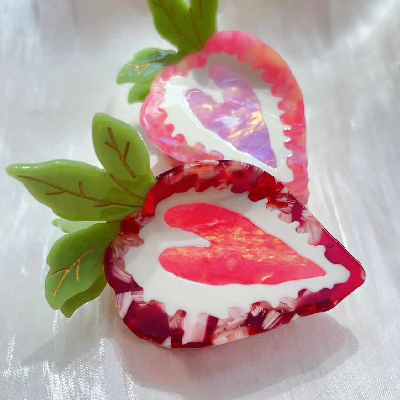 Handmade red strawberry hairpin with pastoral style design on a pink background