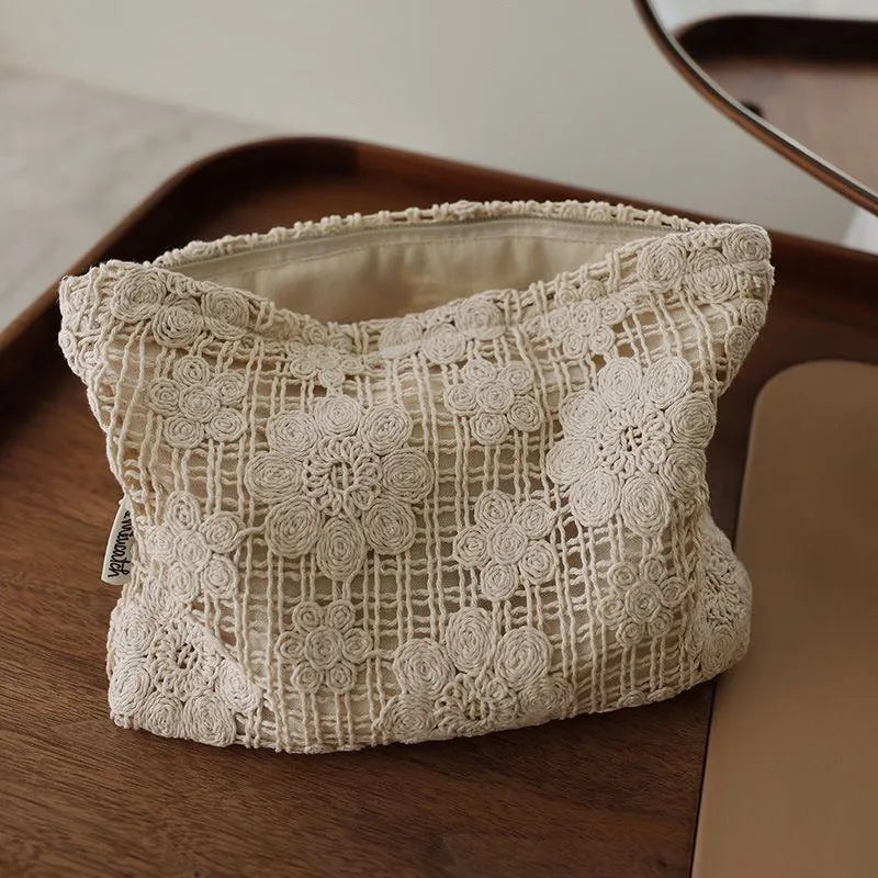 Handmade crocheted floral cosmetic bag with ethnic embroidery on corduroy fabric, showing woven patterns and cutout designs