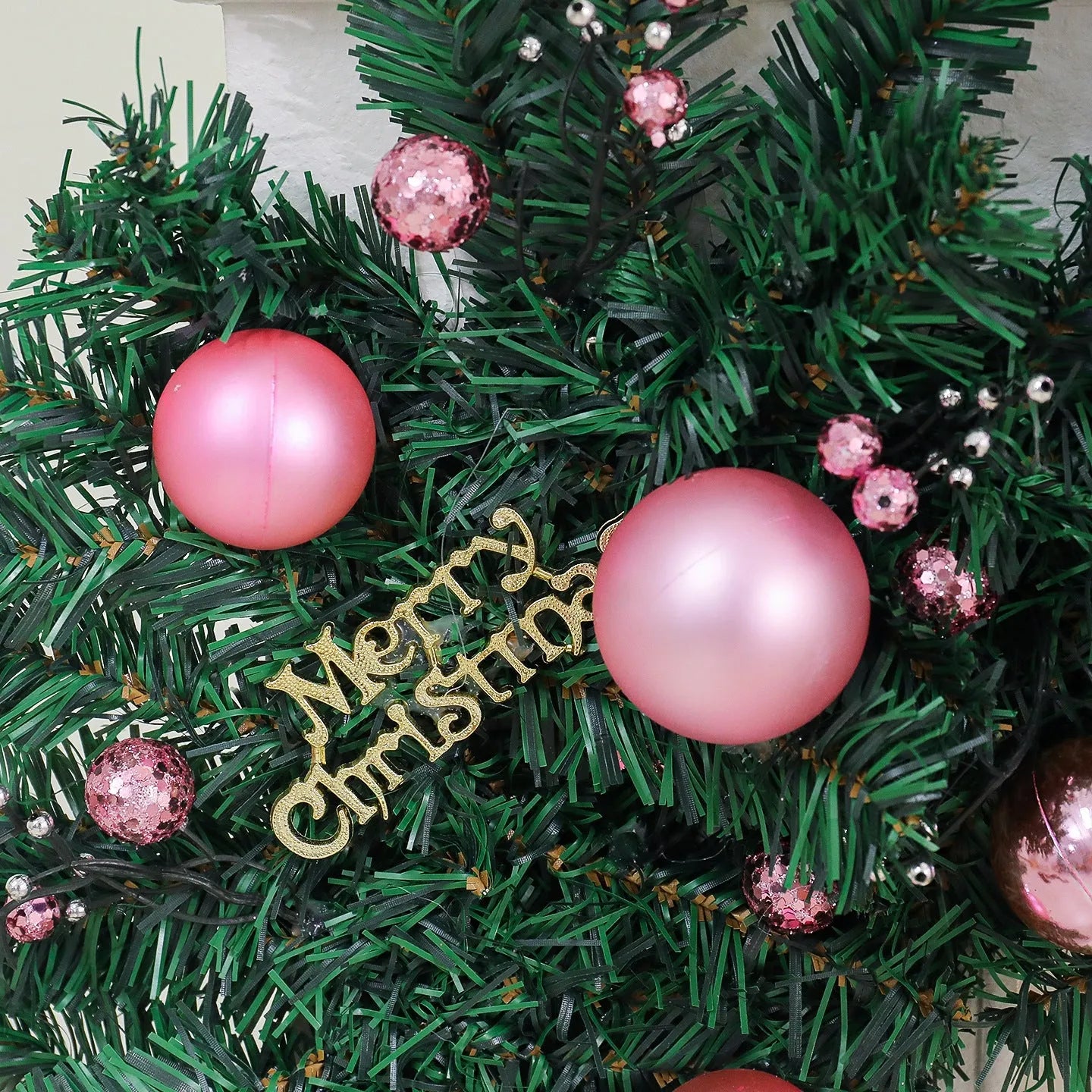 Pink rattan Christmas vine decoration with small fruit ornaments, 2.7 metres long, on a wall display