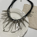 Leather necklace with winding tassel, round beads, and metallic rivet details in a picture colour.