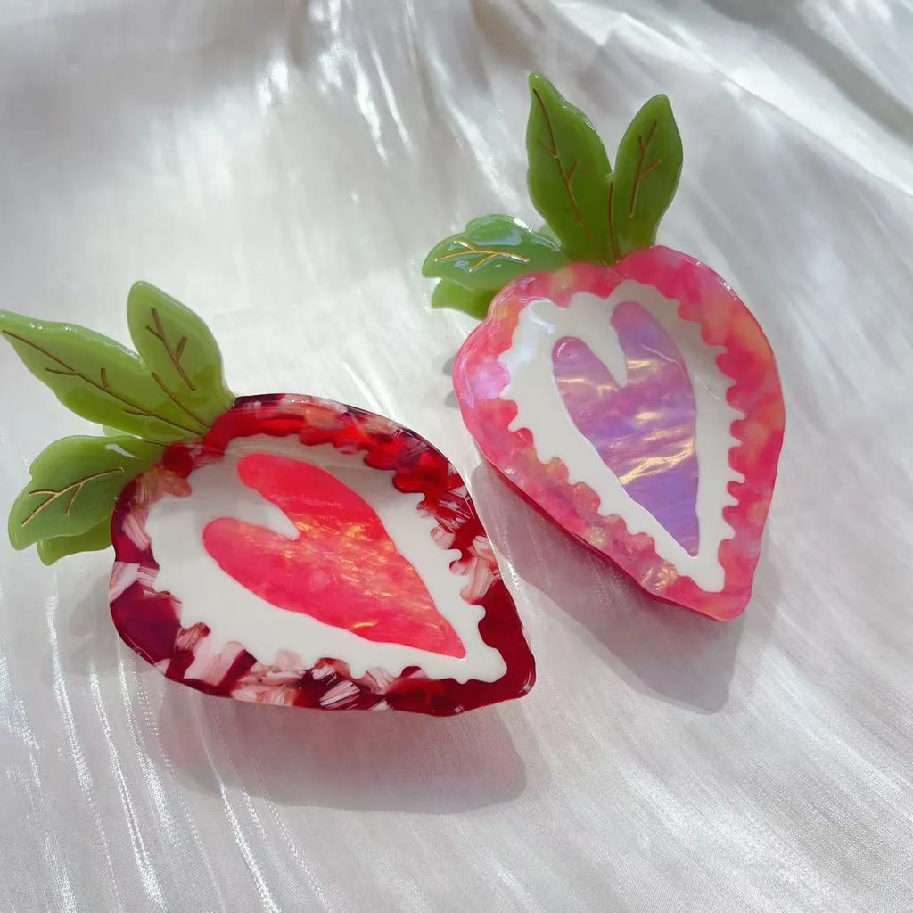 Handmade red strawberry hairpin with pastoral style design on a pink background