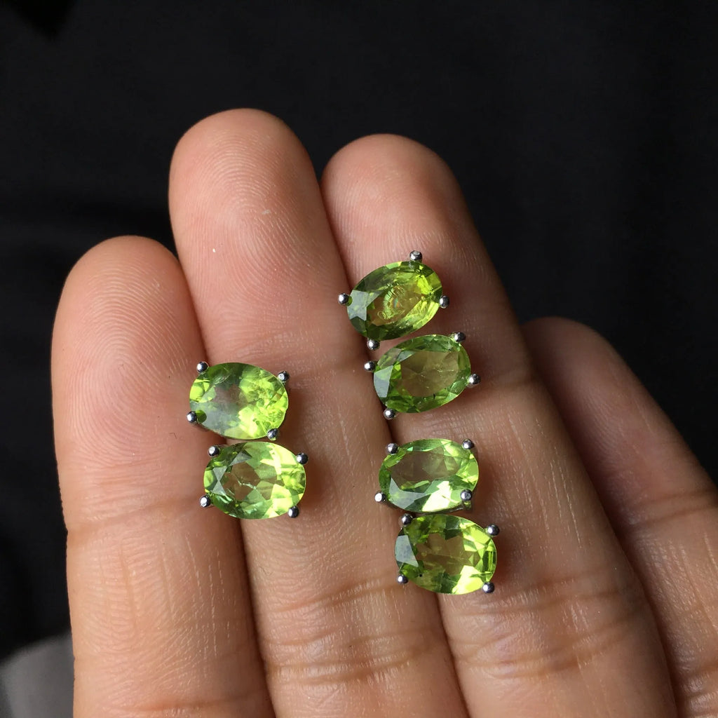 Close-up of grass green olivine stud earrings with elliptical 6x8mm stones in sterling silver setting.