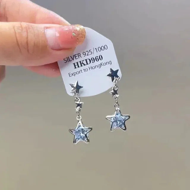 Geometric gold-tone clip-on earrings with a dangling tassel, rhinestone stars, and a heart charm.