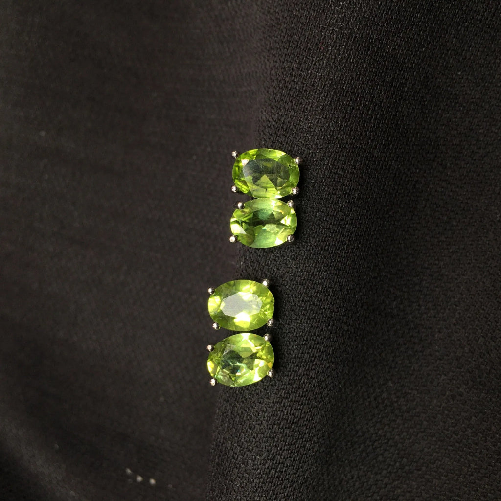Close-up of grass green olivine stud earrings with elliptical 6x8mm stones in sterling silver setting.