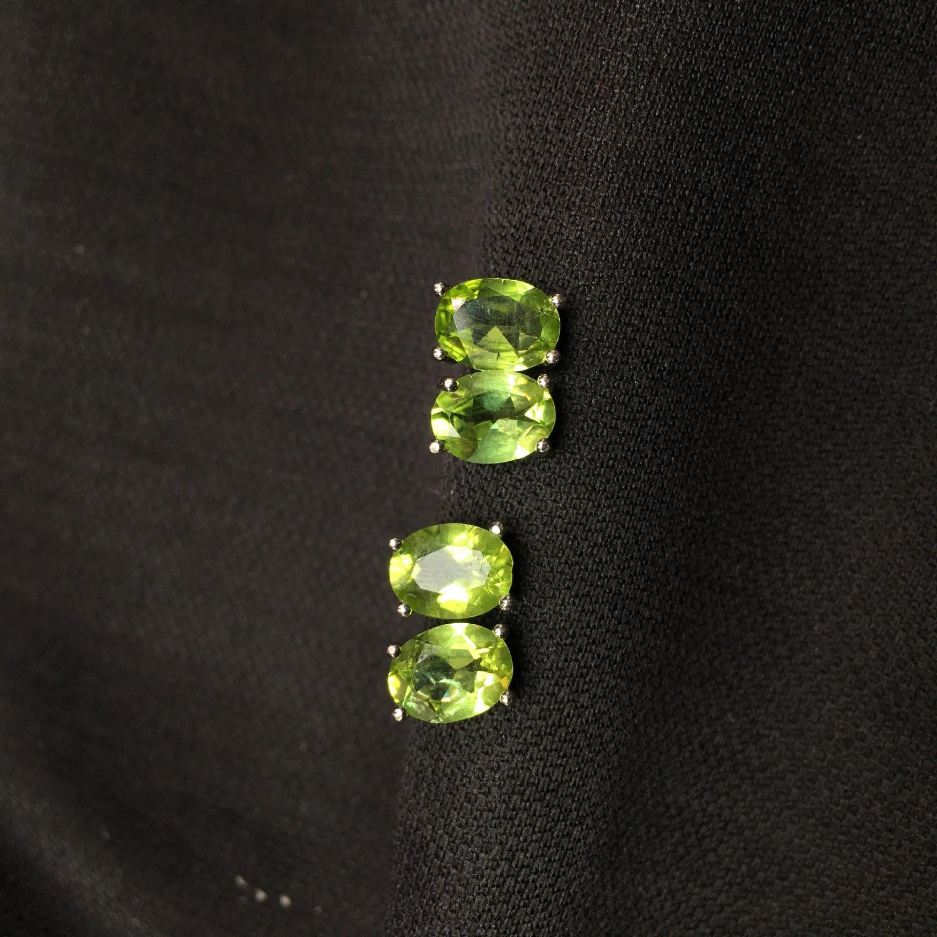Close-up of grass green olivine stud earrings with elliptical 6x8mm stones in sterling silver setting.