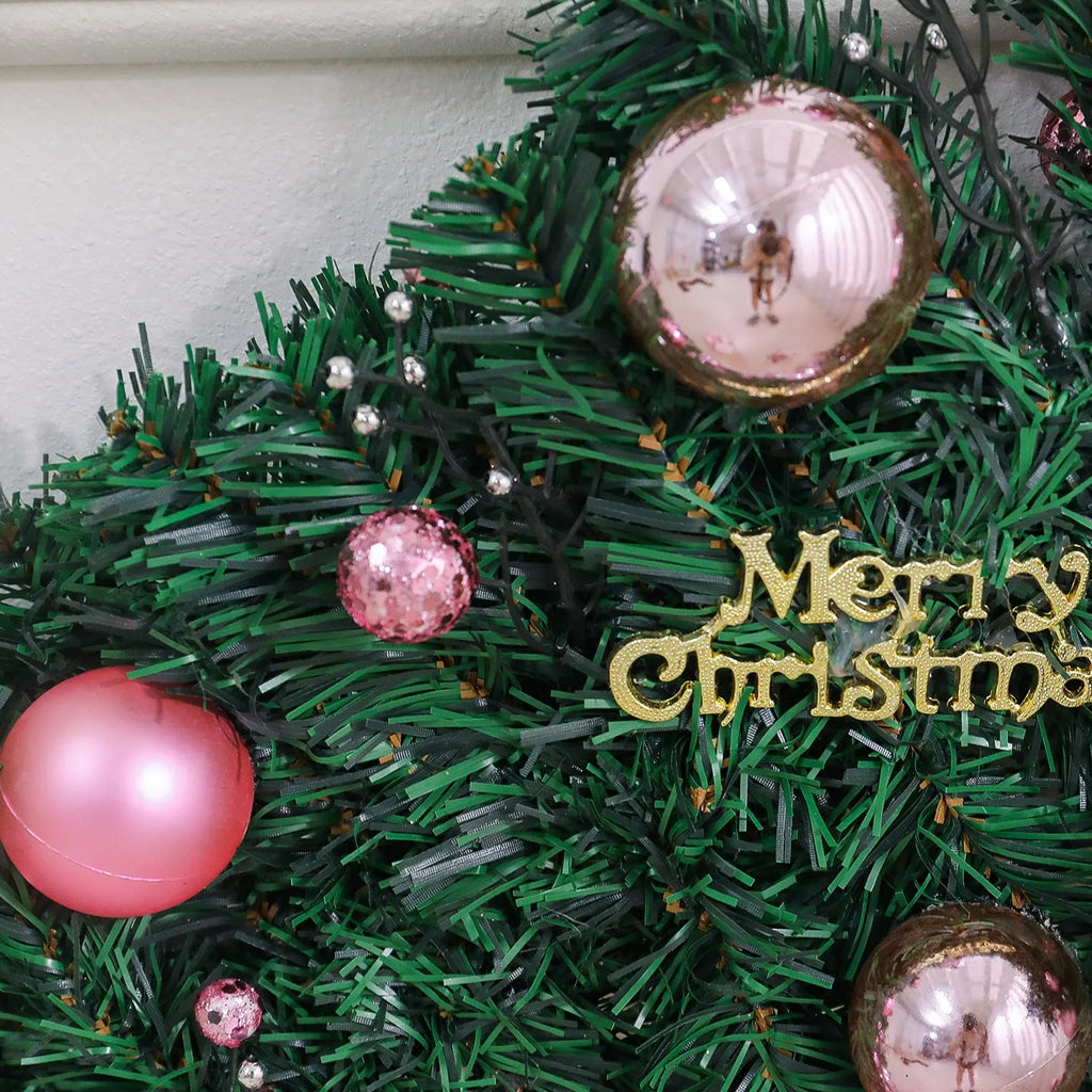 Pink rattan Christmas vine decoration with small fruit ornaments, 2.7 metres long, on a wall display