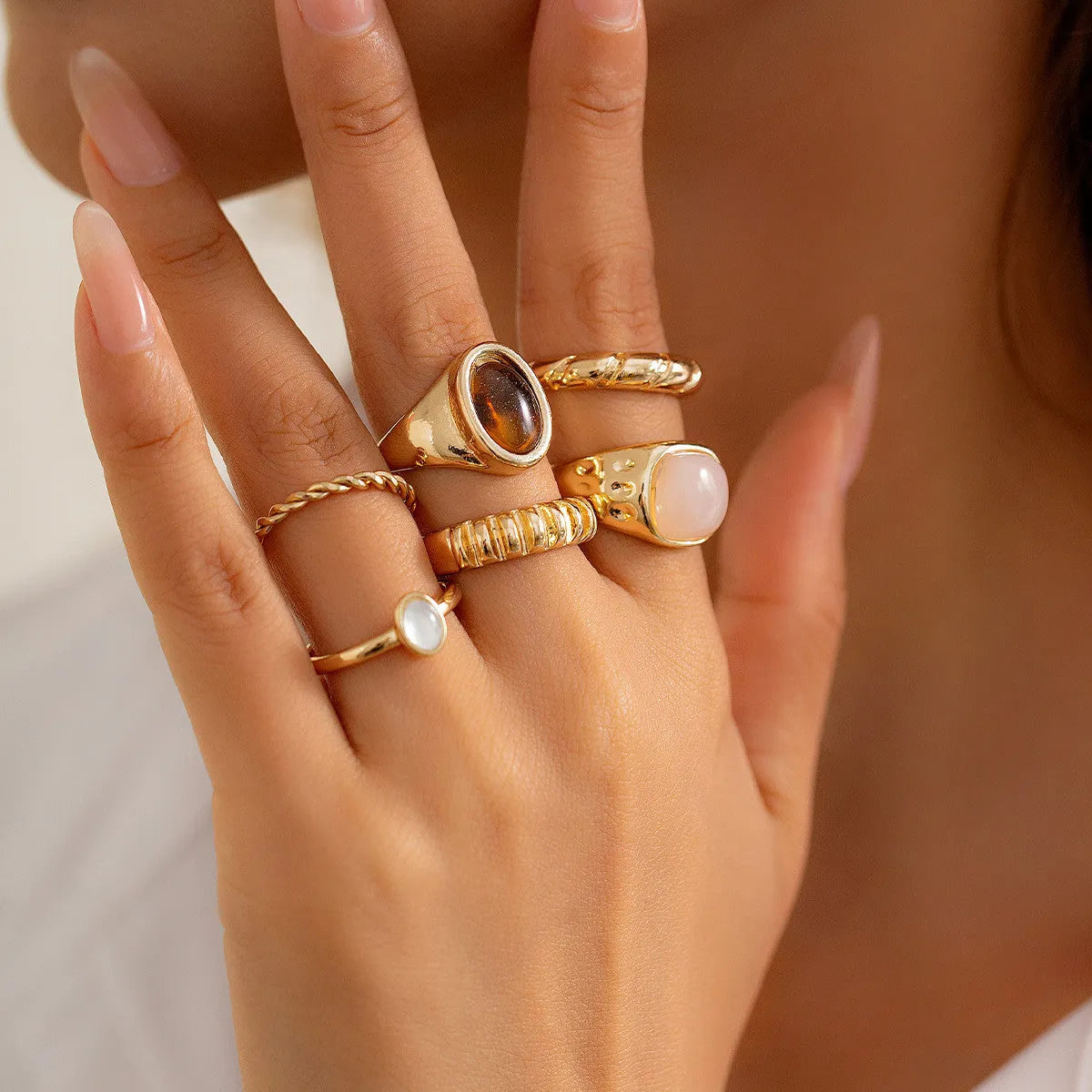 Six irregular geometric alloy rings in light gold colour arranged for display