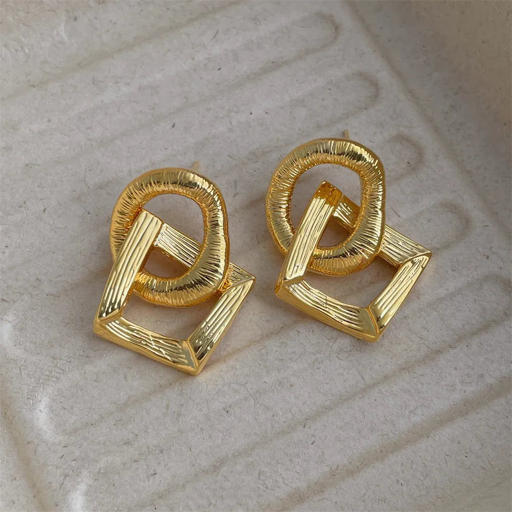 Retro geometric circle pendant earrings with a long drop, shown in gold and silver colour options.