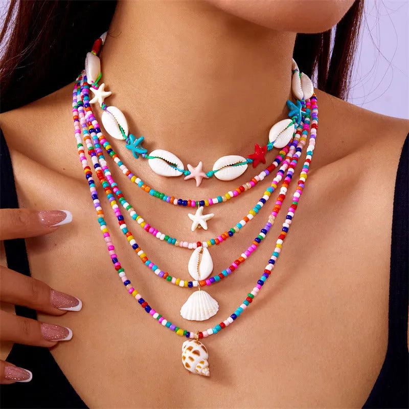 Blue and multi-colour women's multi-layer necklace set with shell, conch, and starfish bead pendants on a white background.