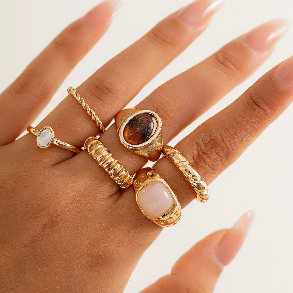Six irregular geometric alloy rings in light gold colour arranged for display