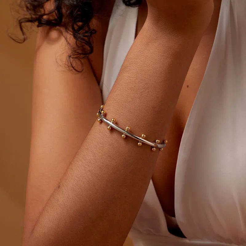 Stainless steel adjustable bracelet with C-shaped links and rivet-shaped bean beads in gold, steel, or steel gold finish