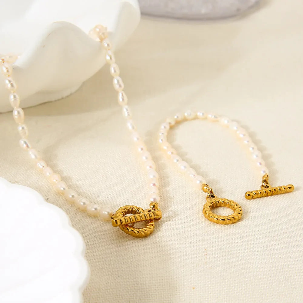 Freshwater pearl and stainless steel geometric pendant necklace and matching bracelet set for women.