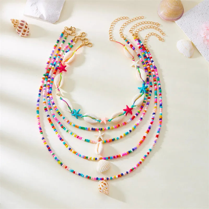 Blue and multi-colour women's multi-layer necklace set with shell, conch, and starfish bead pendants on a white background.