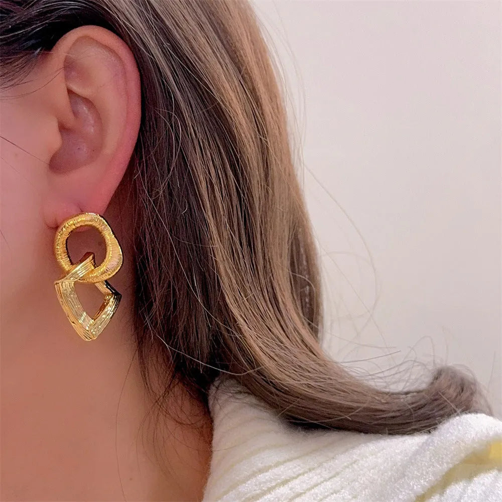 Retro geometric circle pendant earrings with a long drop, shown in gold and silver colour options.
