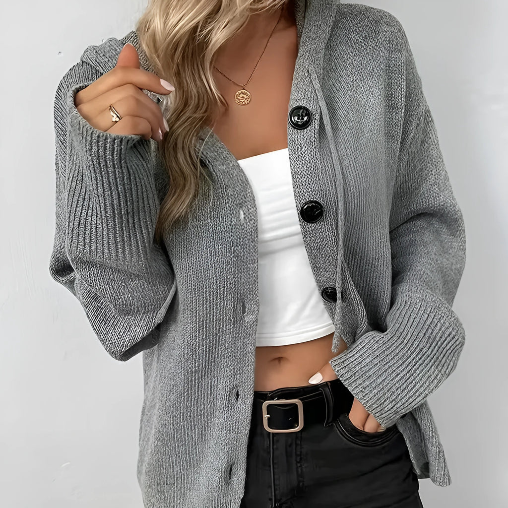 A thick grey cotton hooded cardigan sweater on a hanger, showing its single-breasted front and long sleeves.