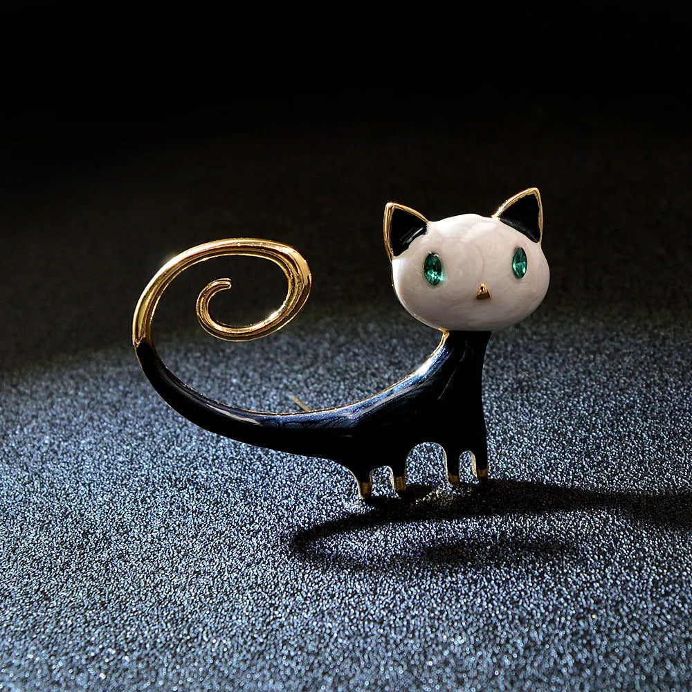 Close-up of a white alloy brooch with a painted tail-up kitten design.