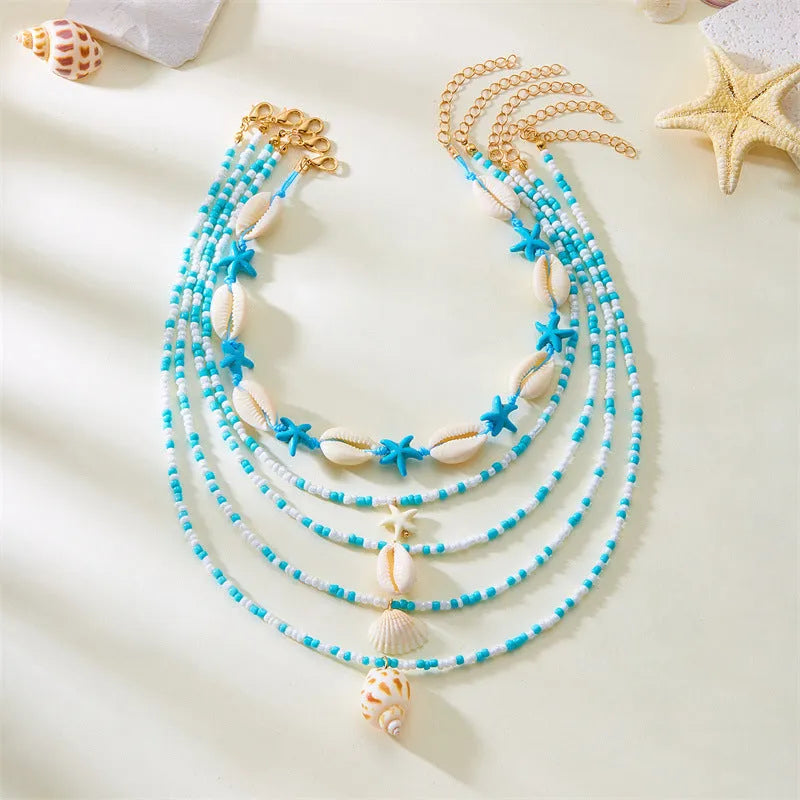 Blue and multi-colour women's multi-layer necklace set with shell, conch, and starfish bead pendants on a white background.