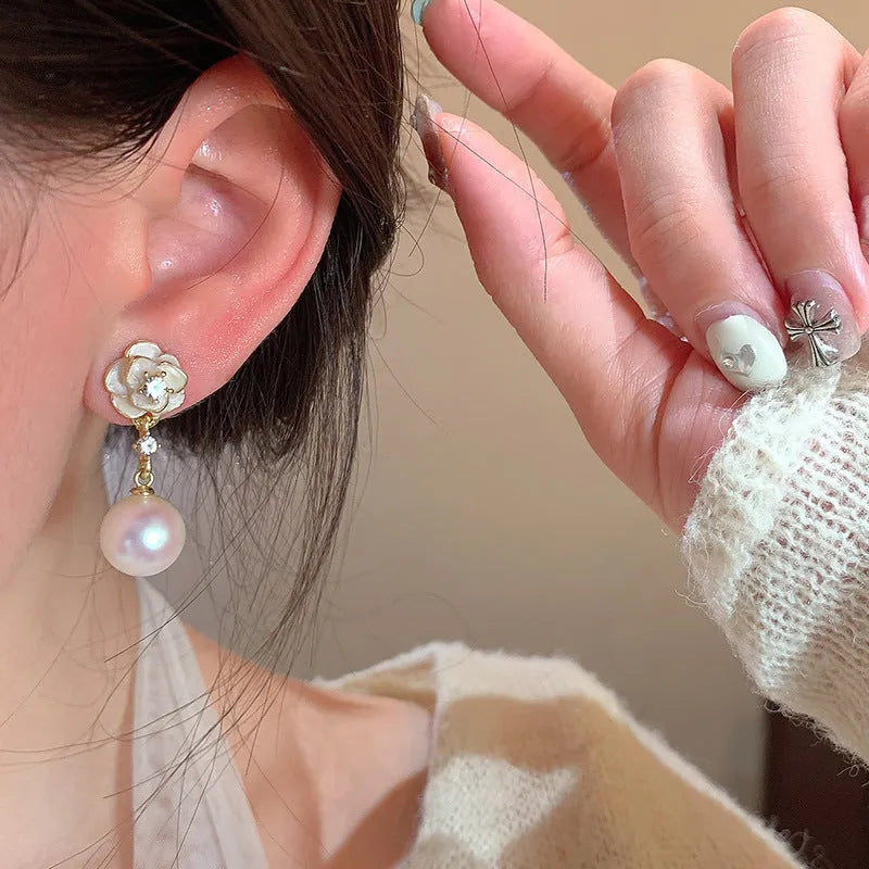Close-up of camellia flower-shaped stud earrings for women in a pearl-like finish.