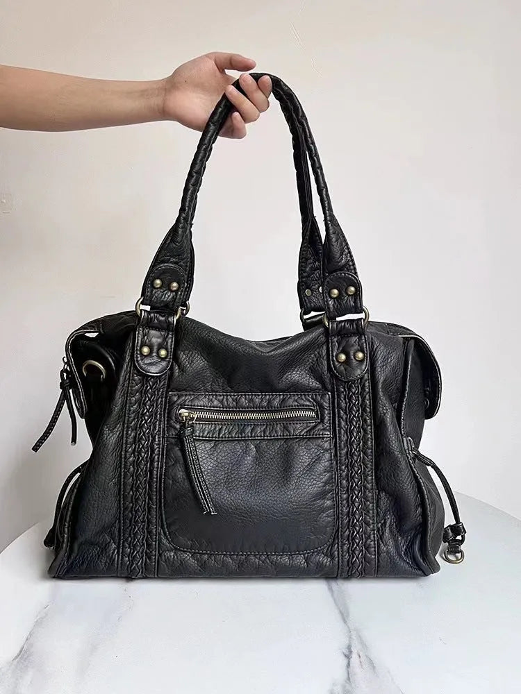 Women's retro messenger bag in bright black with golden edge, showing internal zipper compartments and weaving details
