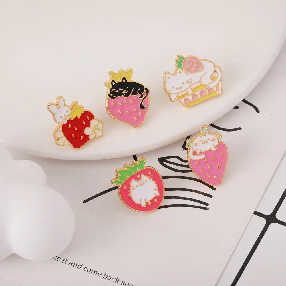 Alloy brooch with a cute cat, strawberry, and dripping oil design in metallic colours.