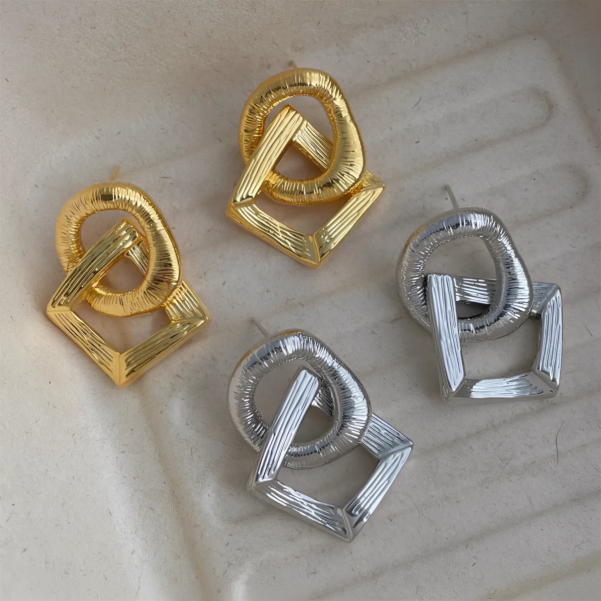 Retro geometric circle pendant earrings with a long drop, shown in gold and silver colour options.