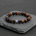 Handmade elastic bracelet with yellow, purple, and red natural tiger-eye stone beads in a geometry shape.