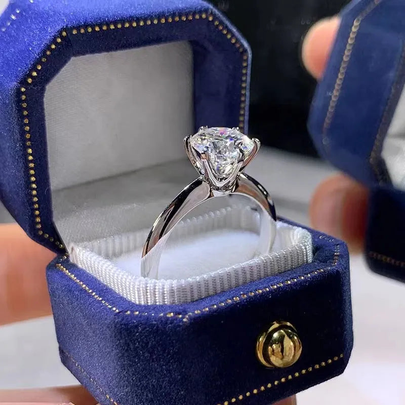 White gold plated six-claw zircon ring with a geometric design on a finger.