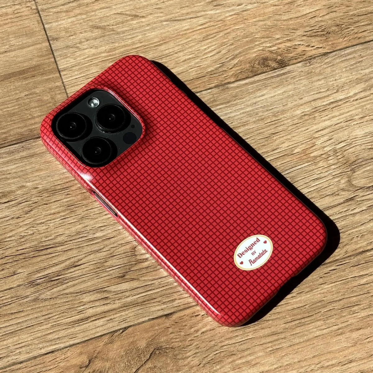iPhone 15 Pro Max case with red and orange plaid pattern in glossy and frosted finishes
