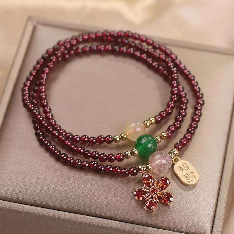 Women's crystal bracelet with pomegranate red cherry blossom beads and sequin details on a simple band.