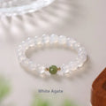 Handmade natural white agate and Hetian jade crystal bracelet with cinnabar inlay on a wrist.