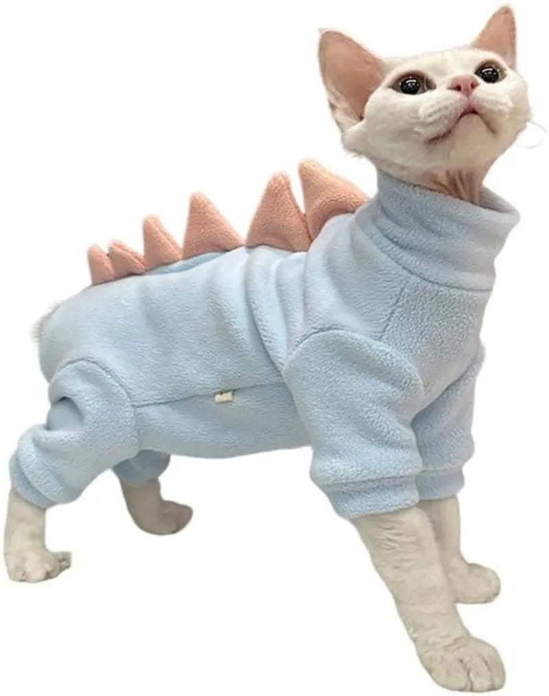 Sphynx cat wearing green dinosaur costume with tail and spikes, showing full-body fleece outfit