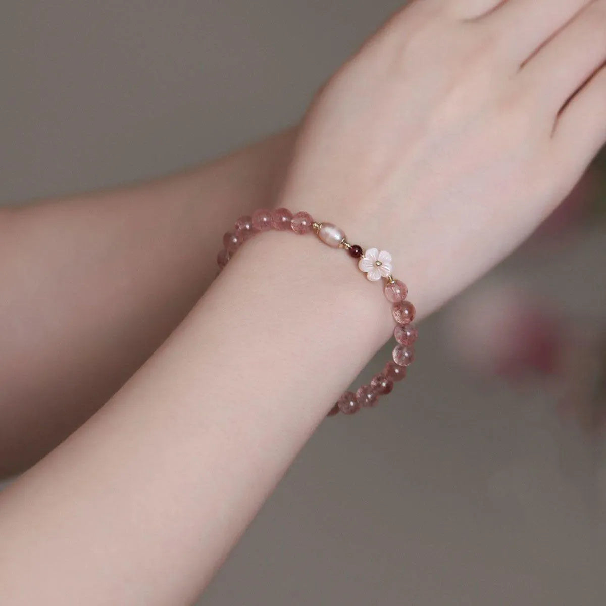 Strawberry quartz crystal bracelet with peach blossom floral design on wrist, showing adjustable 18-20cm length