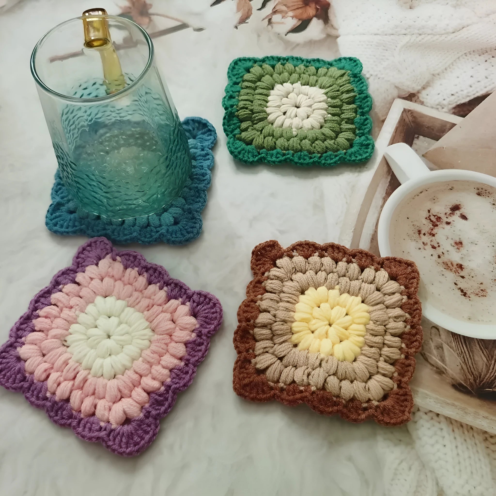 Crocheted grandmother lattice insulated cup placemat in wool, shown in one of four colours