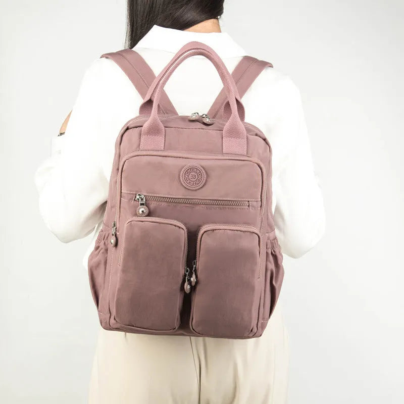 Large purple waterproof travel backpack showing front organiser pocket and internal laptop and camera compartments.