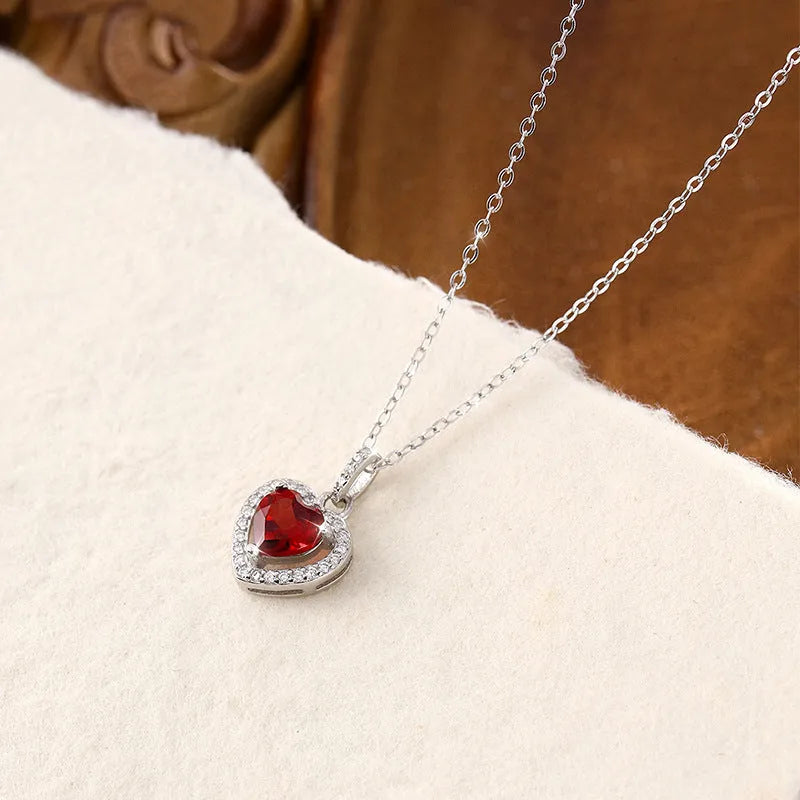 Heart-shaped sterling silver necklace with a coloured gemstone on an adjustable cross chain.