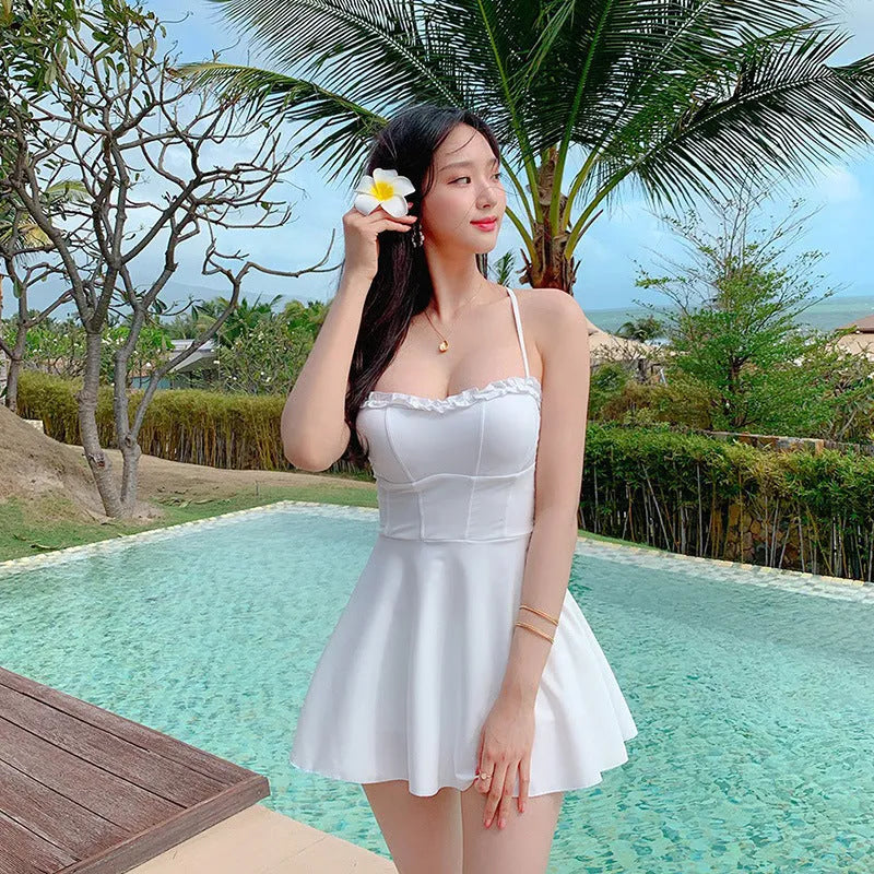 A white women's one-piece swimsuit with a skirted design, made from nylon.