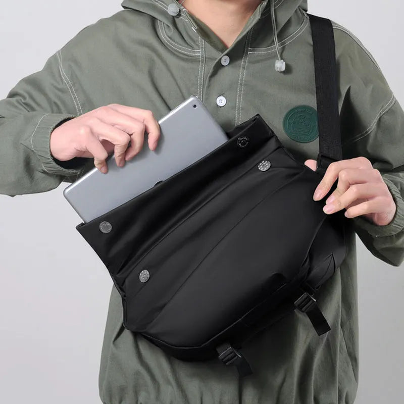 Men's grey crossbody bag with motorcycle sling strap, horizontal square shape, and zipper opening