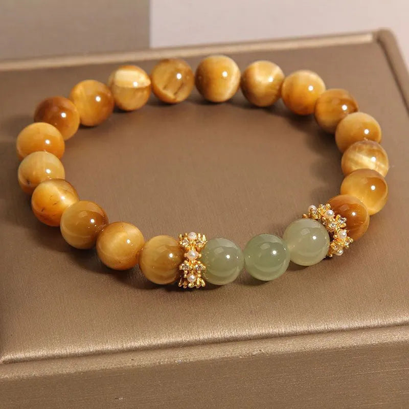 Natural yellow tiger's eye stone bead bracelet with gold gourd charm on a white background.
