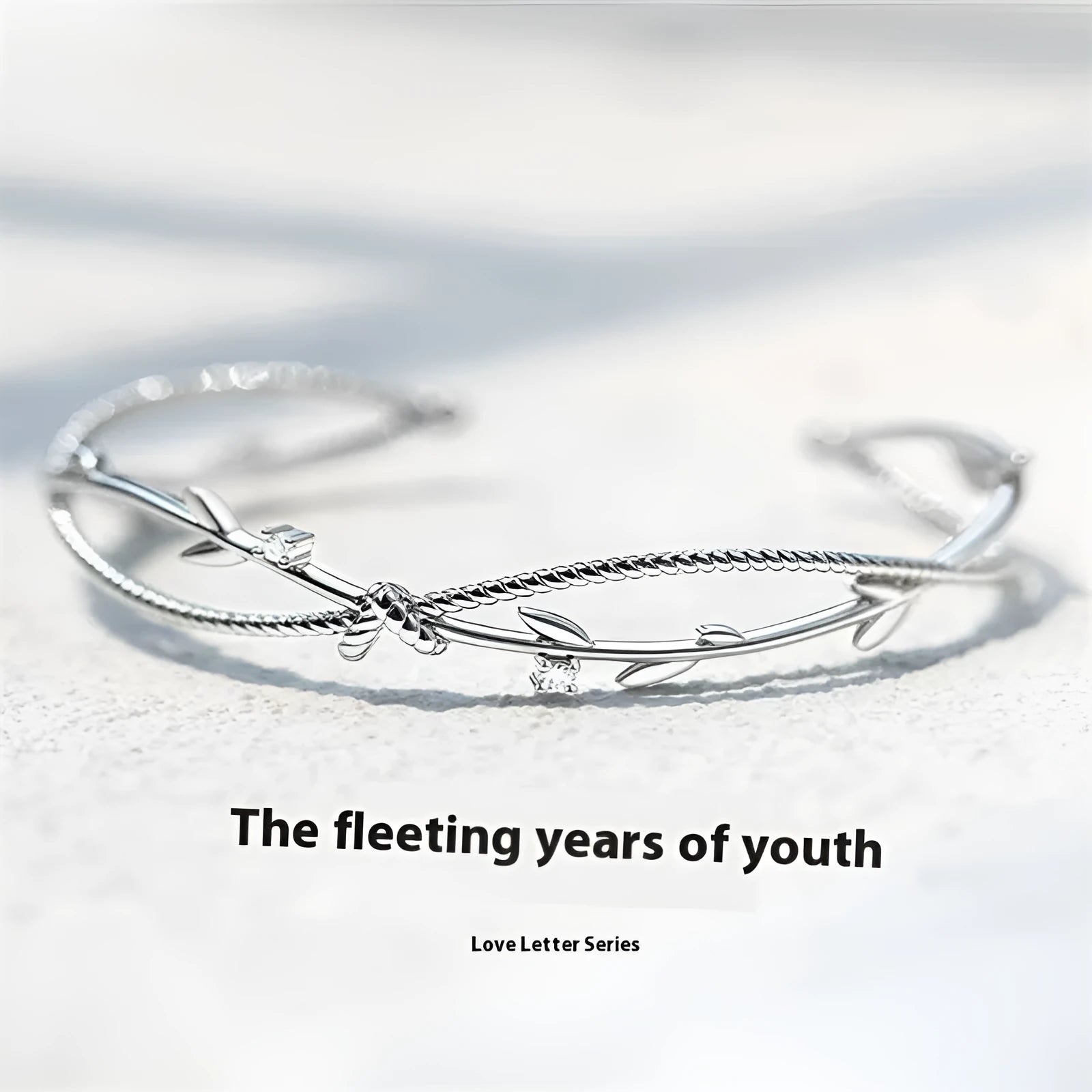 Close-up of an adjustable white gold coloured copper bracelet with a twisted branch and sprout design.