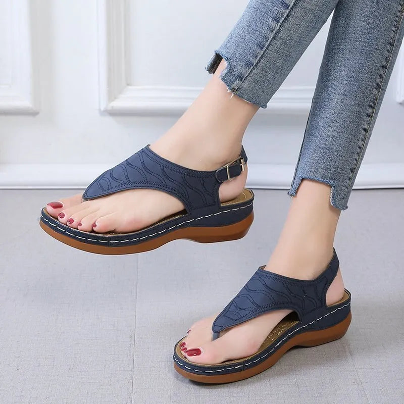 Women's casual wedge heel flip flop sandals with an adjustable buckle strap on the back, shown in a solid colour.