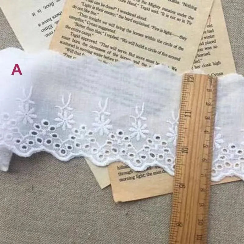 Reel of white embroidered cotton lace trim with a cutout design, showing four different width styles for DIY sewing.