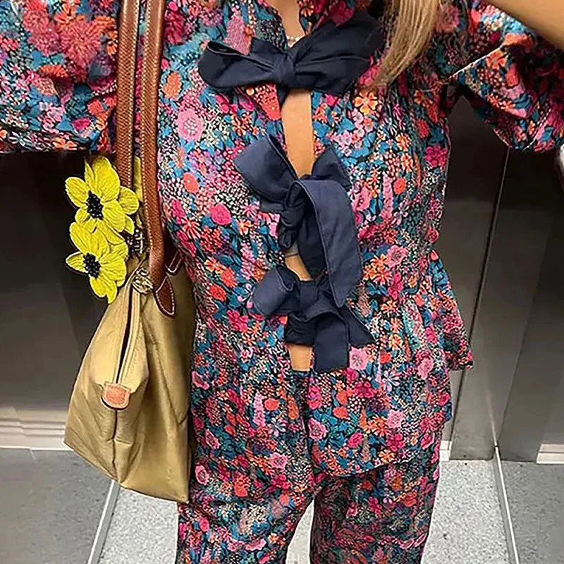 Floral printed trousers suit with tie-neck top and puff sleeves in picture colour, showing front and back views