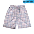 Man wearing grey plaid casual shorts with an elastic waistband, on a beach.