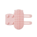 Black silicone cat grooming comb with adjustable strap attached to a table leg, showing rounded teeth for hair removal
