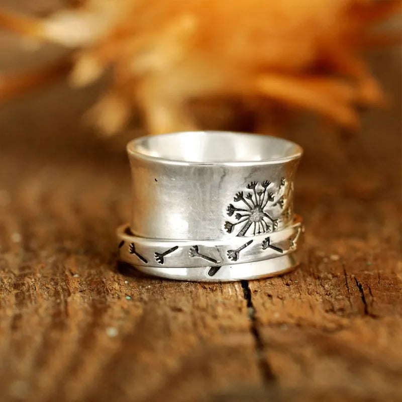 Silver flower ring on a finger showing its rotatable band and adjustable open design.